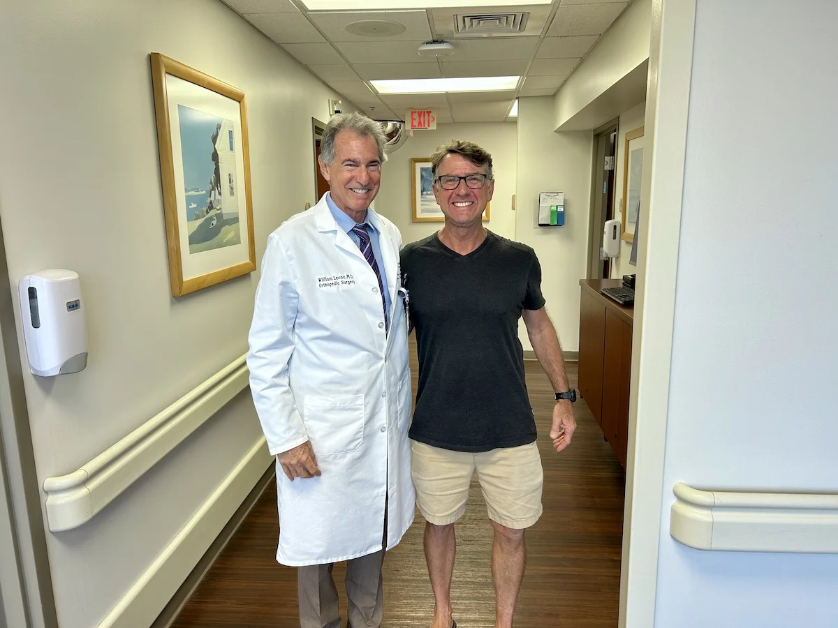 Larry Heath stands with Dr. Leone. Happy about his SPAIRE total hip.